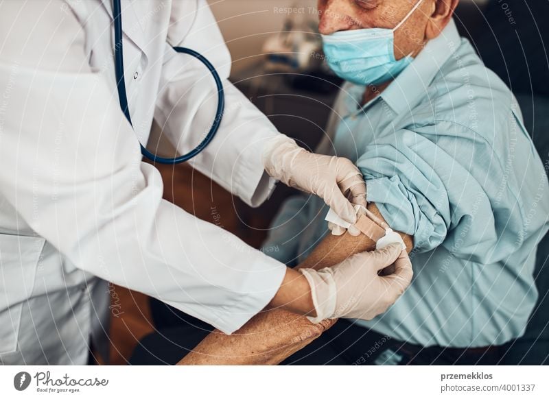 Doctor putting a plaster in place of injection of vaccine to senior man patient. Covid-19 or coronavirus vaccination person hospital doctor medical medicine