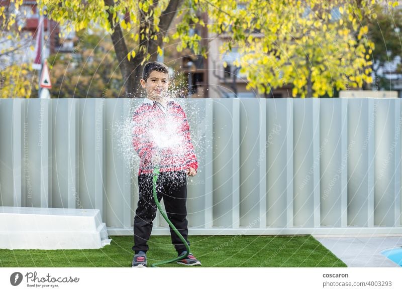 Little boy watering the grass in the garden action activity child childhood children drops enjoy family fountain fresh fun gardening green happiness happy hose
