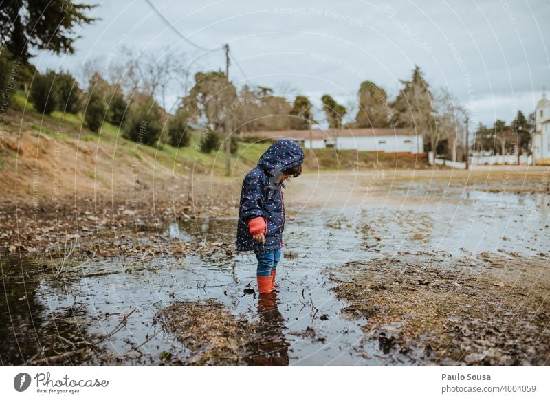 Child with red rubber boots playing on a puddle childhood Puddle Rain Authentic Human being Playing Rubber boots Water Wet Exterior shot Joy Colour photo