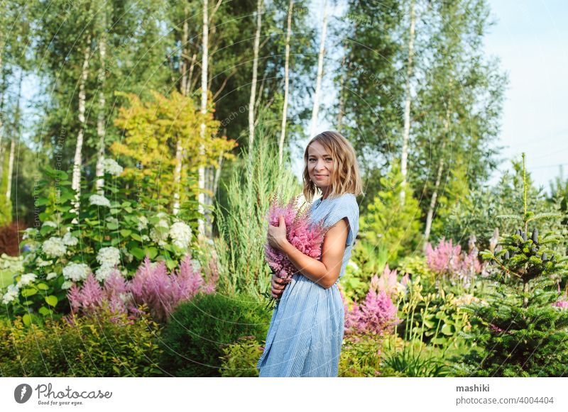 woman gardener posing with bouquet of astilbe flowers in private garden. Country living and landscape design concept gardening female plant happy caucasian
