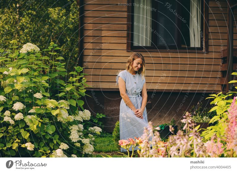 young happy woman walking in private garden, posing at wooden country house. gardening female plant caucasian lifestyle gardener farmer active agriculture