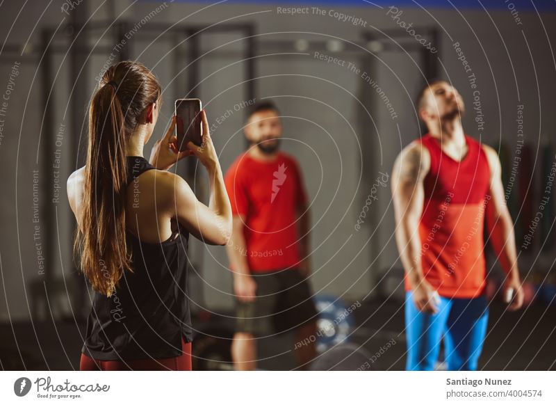 Woman taking picture with smartphone in gym. crossfit functional training health sport fitness workout exercise lifestyle healthy adult sportswear gymnastics