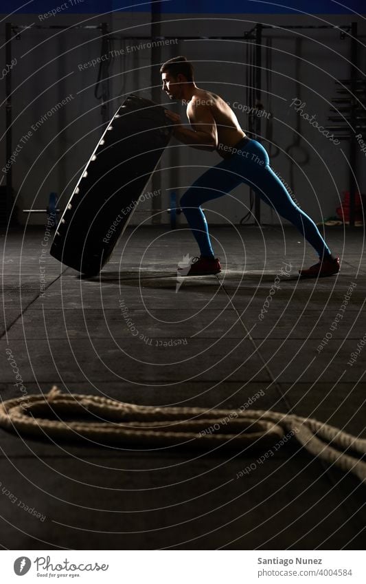 Man flipping over a tractor tire. crossfit functional training gym health sport fitness workout exercise lifestyle healthy adult sportswear gymnastics equipment