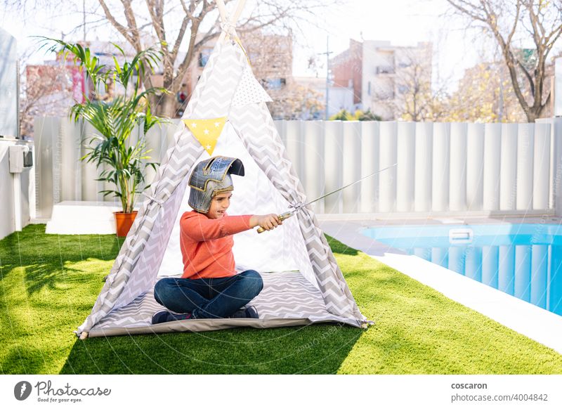Little boy playing in a indian tent caucasian child childcare childhood clothes costume cute educational feather fun funny game garden grass happiness happy