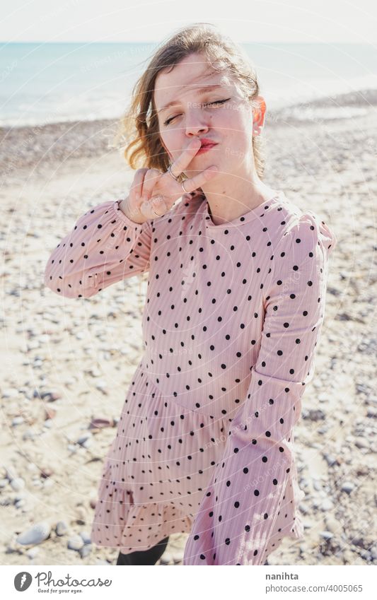 Young woman wearing a pink dress at the beach holidays trendy kawaii casual lifestyle blonde natural beauty attractive pretty fashion model wind windy sea shore