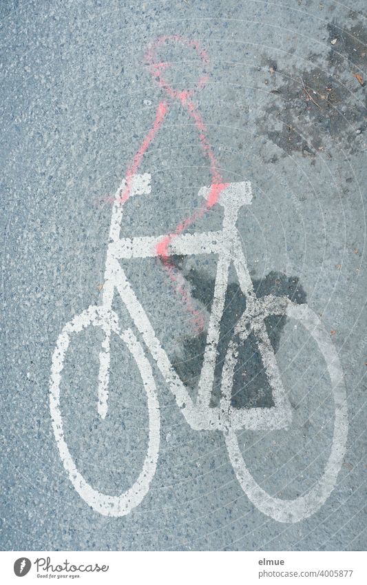 A joker has painted a stick figure with red paint on a white bicycle - pictogram on the grey, asphalted road / road marking Pictogram Bicycle Stick figure
