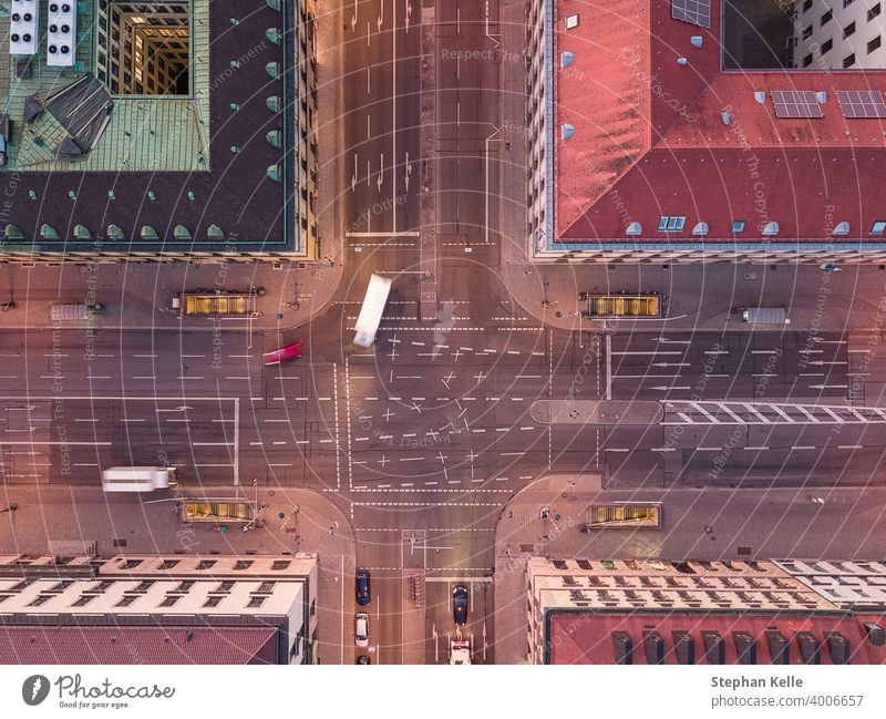 Aerial shot of an urban crossing road in a city with bend of cars from a top down view at the street between houses. turn motion traffic dynamic authentic