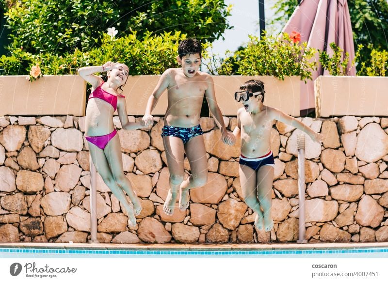 Three kids jumping into a pool action active blue child childhood children playing children vacations copy space cute dive enjoyment family friends fun girl