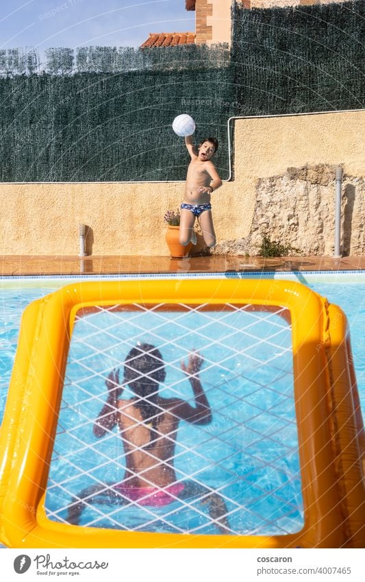Two kids playing with a ball on a pool active activity aquatic beach blue boy caucasian child childhood children energy family fun game girl goal guy happy