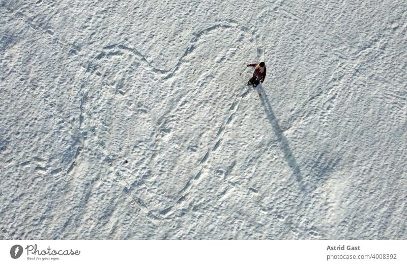 Aerial drone shot of a snow school runner making a trail in the shape of a heart in the snow Aerial photograph Woman Sports Winter Snow Winter sports