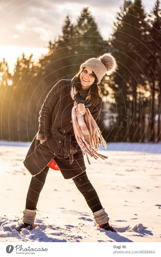 Fun-loving woman standing on a snow covered field at the edge of the forest in the background winter sun Joie de vivre (Vitality) Winter wonderland Winter sun