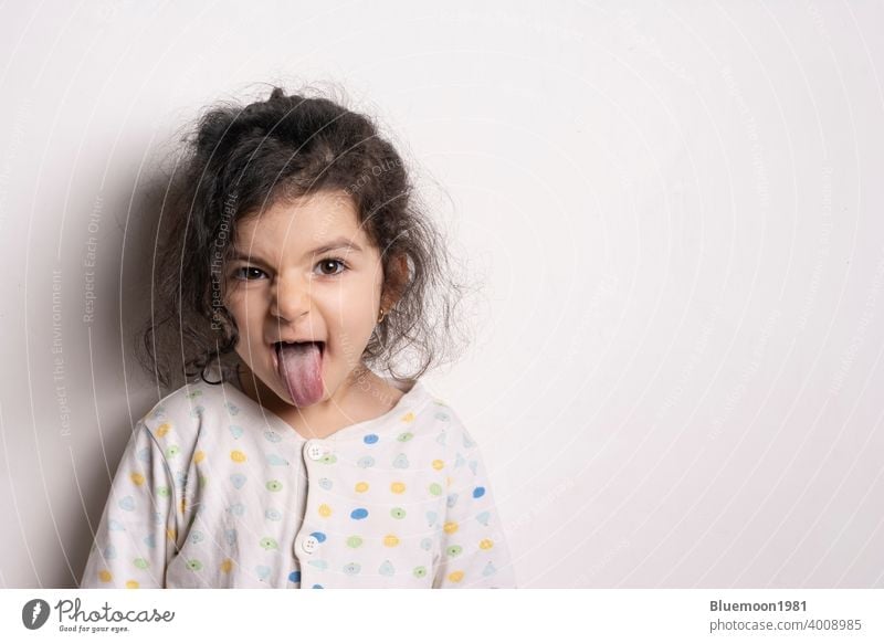 Little girl portrait with outside tongue girl shows tongue funny posture -  a Royalty Free Stock Photo from Photocase