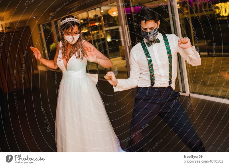 Young couple with surgical masks dancing on their wedding marriage engagement bride covid face mask party safe coronavirus covid19 covid-19 pandemic happy