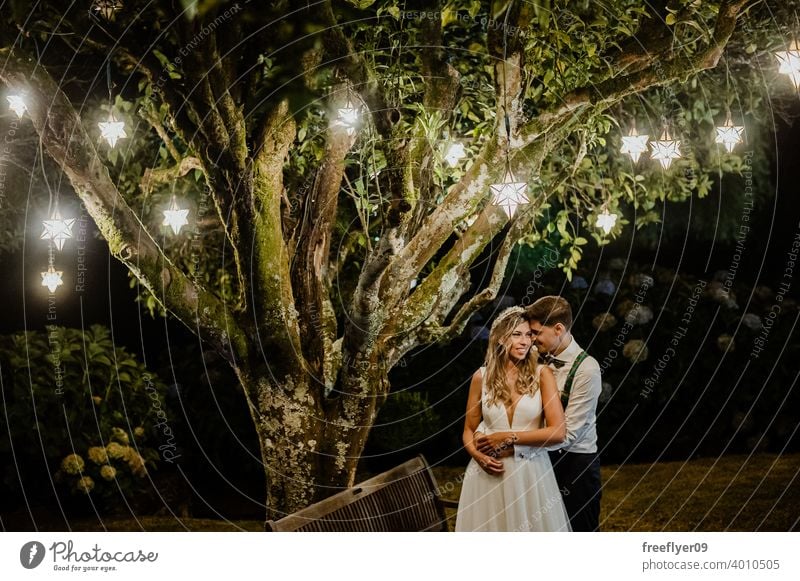 Couple under a tree on their wedding day marriage engagement bride people young attractive copy space night lights pendant nature outside love groom couple