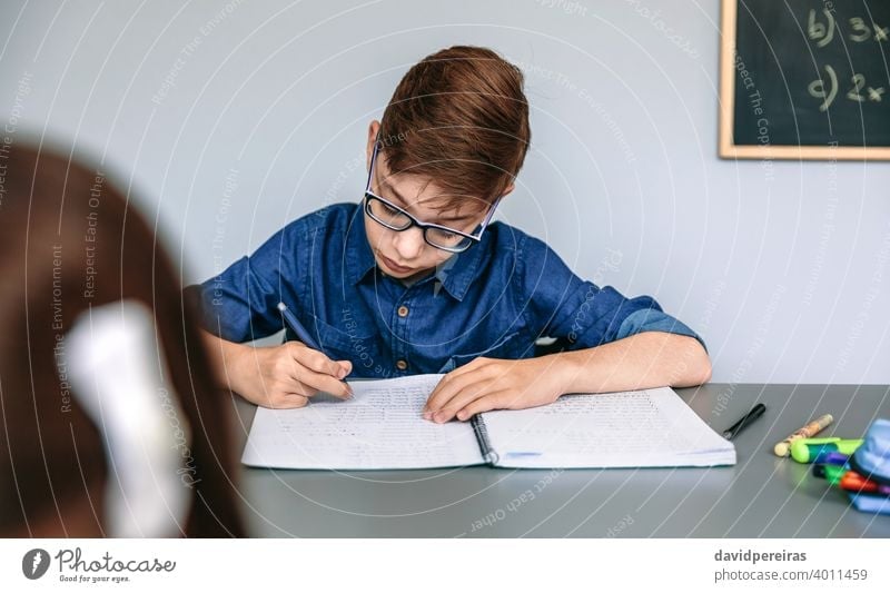Teenager writing in notebook at school teenager student classroom concentrated education studious people young girl female two boy person child kid children