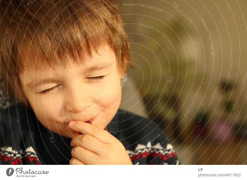 child with closwd eyes smiling at the camera and trying to eat something future outlook Children's game Mysterious Peaceful smile Connection moment activity