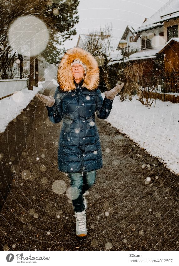 Frau spaziert bei Schneefall durch die Straßen spaziergehen walk winterwalk mantel kunstpelz lachen lächeln wärme schneefall kälte weiß jacke bäume dorf freude