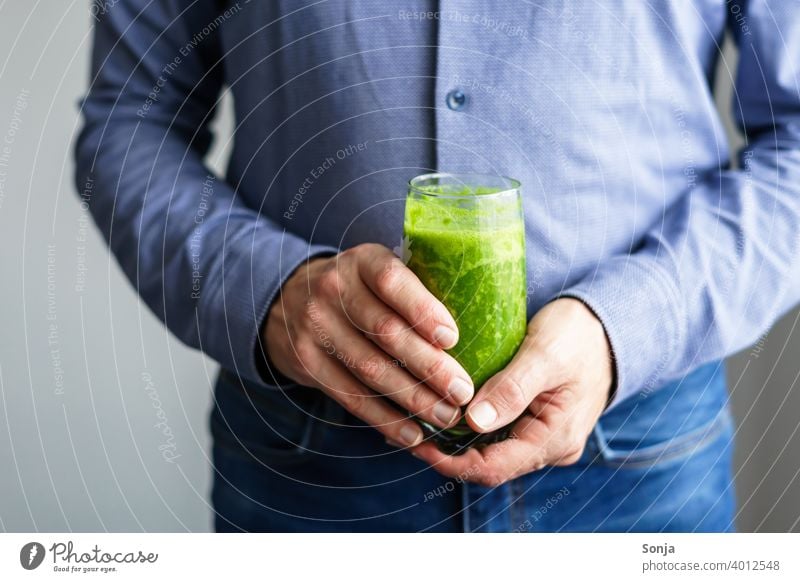 Man holding a glass of green smoothie in his hands Green Glass 50 plus Shirt Jeans partial view Hand stop Business Healthy Eating Vitamin Diet Vegetarian diet