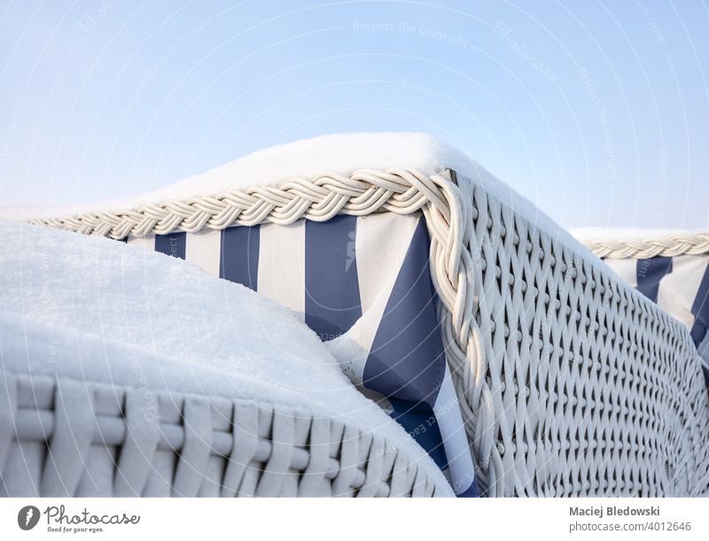 Close up picture of roofed wicker beach chairs covered with snow. winter concept close up sky vacation blue travel tourism sunbath relax outdoor relaxation