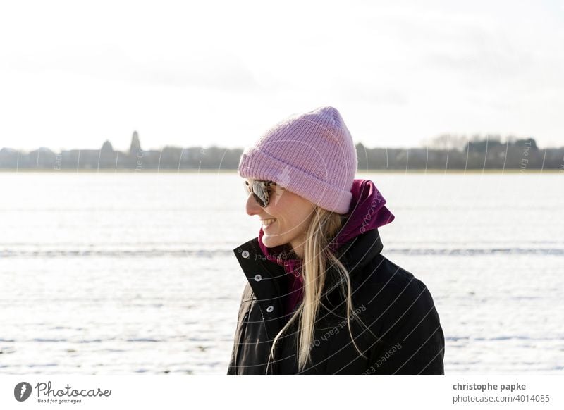 Woman with cap in snowy landscape Cap Cold Winter Smiling Blonde Sunglasses Bright portrait Young woman Exterior shot Snow Nature Colour photo Human being
