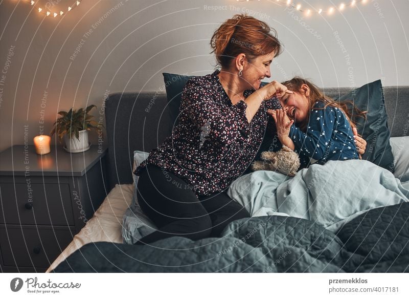 Mother playing with her little daughter in bed, having fun before going sleep child mother family woman caucasian female home girl parent together happiness