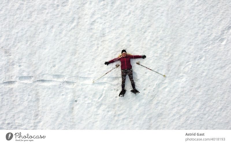 Aerial shot with a drone of a snowshoer lying in the snow Aerial photograph Woman Sports Winter Snow Winter sports snowshoeing Human being droning Lie Laughter