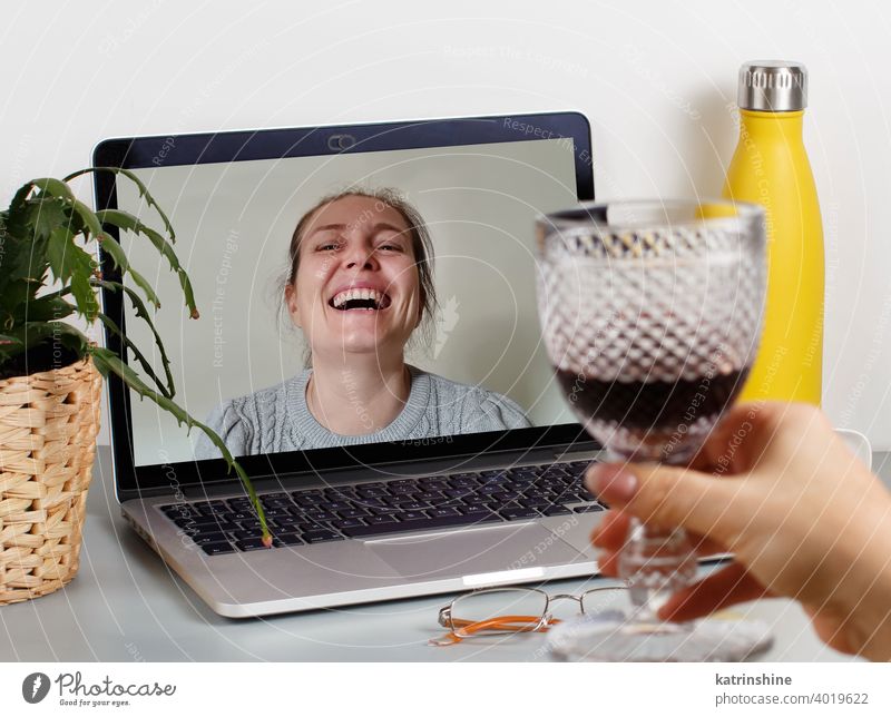 Two friends drinking wine while having a video call glass women laptop isolation Social distancing videocall red wine smile laugh plant succulent grey person