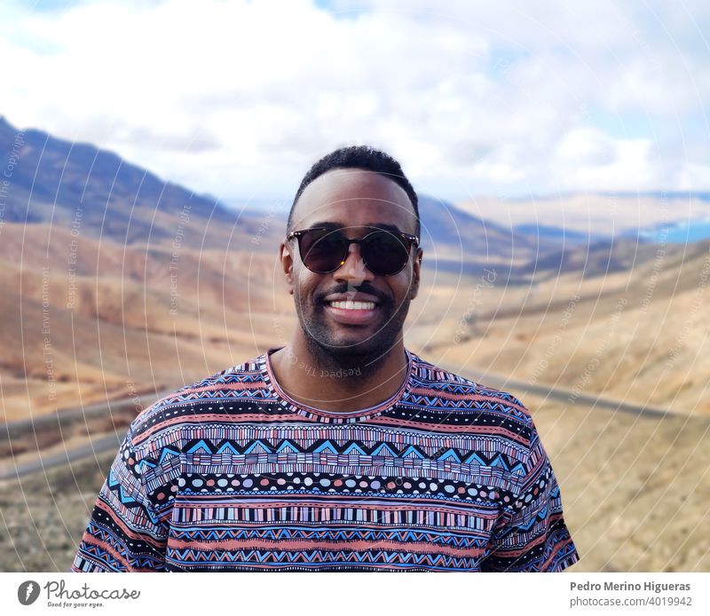 Black man portrait in a Fuerteventura viewpoint. isolated street beauty cheerful guy outdoors casual attire smiling person photogenic adult smile happy young