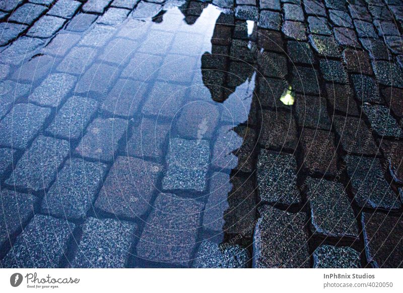 Man walking on a street across a puddle of water Water Street Europe tiles Perspective floor texture Blue Calm Reflection reflections Reflection in the water