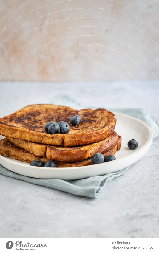 Side view of three slices of delicious French toast with blueberries on a plate on grey background, minimalistic style with copy space french toast