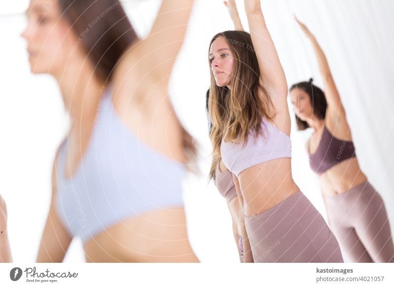 Group of young sporty attractive women in yoga studio, practicing yoga lesson with instructor, standing, stretching and relaxing after workout . Healthy active lifestyle, working out indoors in gym