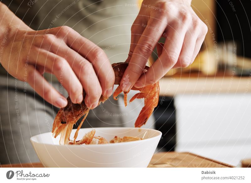 Woman cleaning shrimps for cooking. Process of hands peel shrimps shell prepare prawns seafood red background shellfish dish large tiger cooked crayfish eating