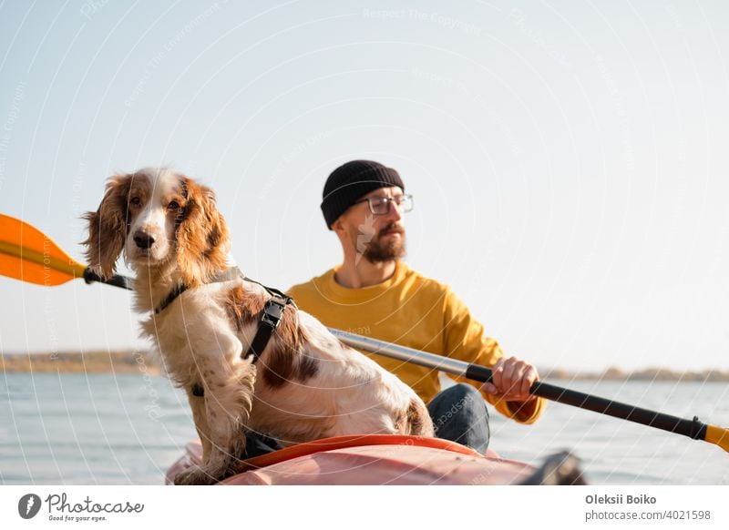 Man with a dog in a canoe on the lake. Young male person with spaniel in a kayak row boat, active free time with pets, companionship, adventure dogs active rest