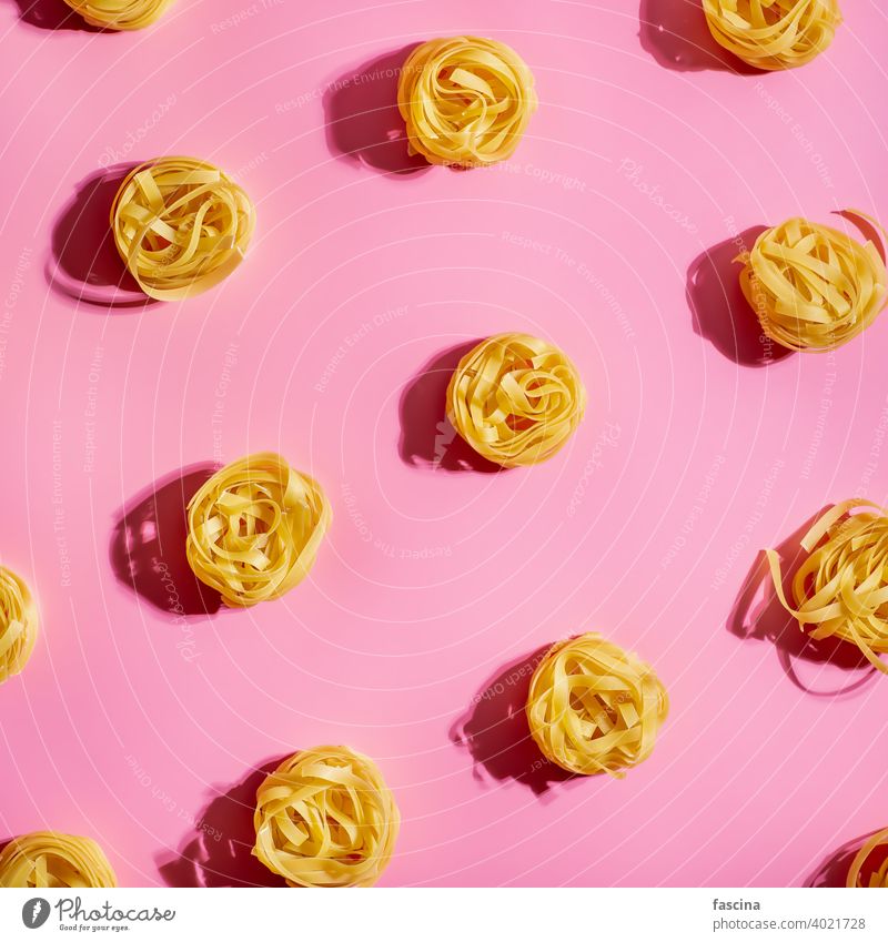 Pasta art with tagliatelle on pink background pasta pattern creative layout top view flat square crop flat lay top down menu concept recipe delicious tasty dry