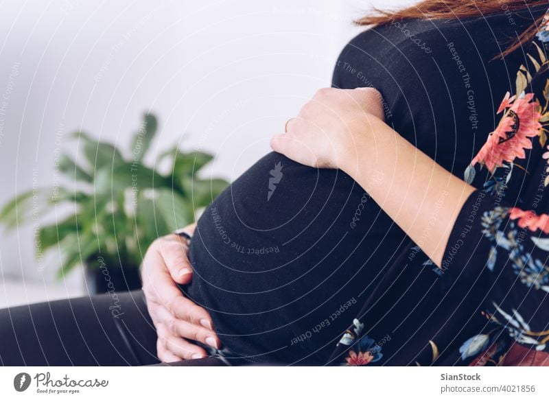 Close up of young pregnant woman touching her belly pregnancy beautiful happy life home maternity care baby concept plants expectation abdomen female mother