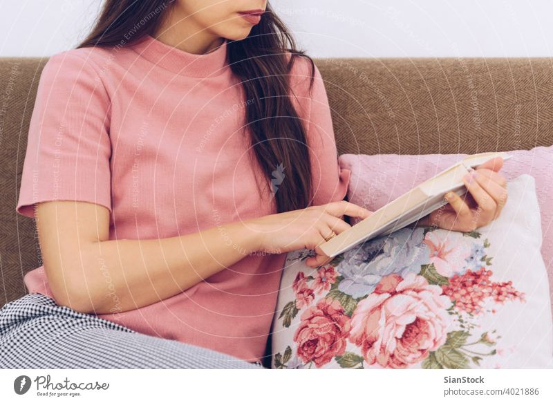 Young woman reading a book on the couch. sofa home female caucasian lifestyle girl white young leisure casual pretty beautiful happy student sitting people