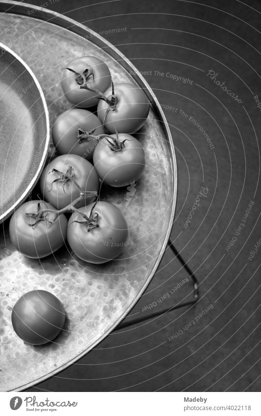 Fresh tomatoes next to a bowl on a decorative round tray with feet in a designer apartment in Rudersau near Rottenbuch in the district of Weilheim-Schongau in Upper Bavaria, photographed in classic black and white