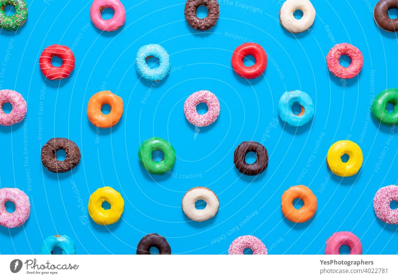 Multicolored donuts top view isolated on a blue background. Glazed doughnuts pattern. above view aligned assorted baked bakery chocolate colorful comfort food