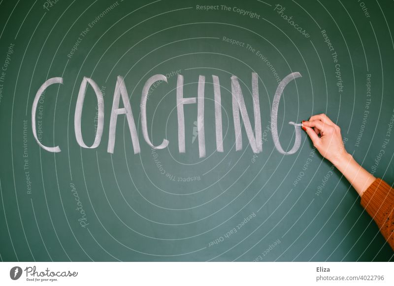 Hand writes the word coaching on a blackboard Coaching Further training Career mindset Business Work and employment Future Education authored Word