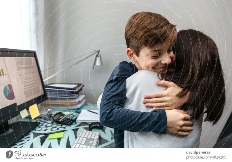 Mother and son hugging while she telecommutes work family conciliation telecommuting mother love copy space happy smiling coronavirus lockdown teen covid-19