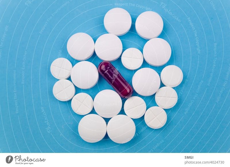 Overhead shot of several white pills and a purple one. Concept of drugs for the treatment of diseases, especially against Covid-19 tablet medicine medical
