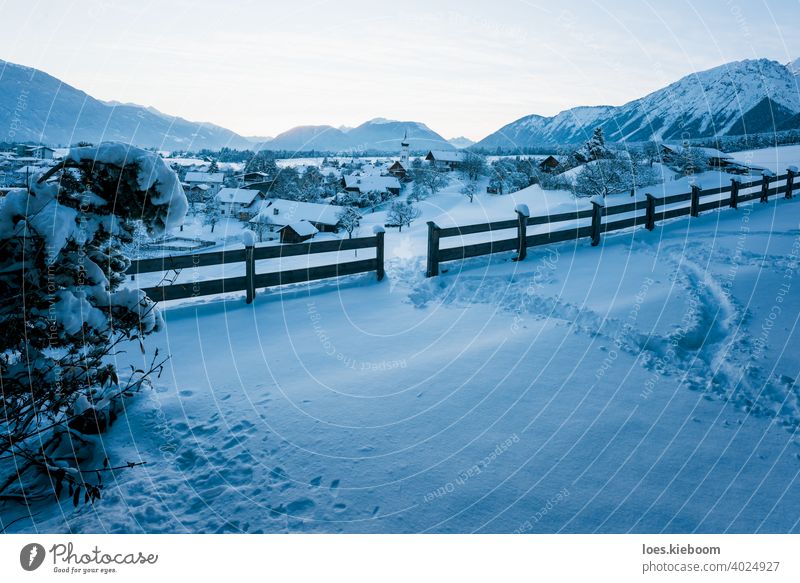 Alpine winter landscape during dusk with view over small Austrian traditional village in Wildermieming, Tirol, Austria snow tirol mountain track fence austria
