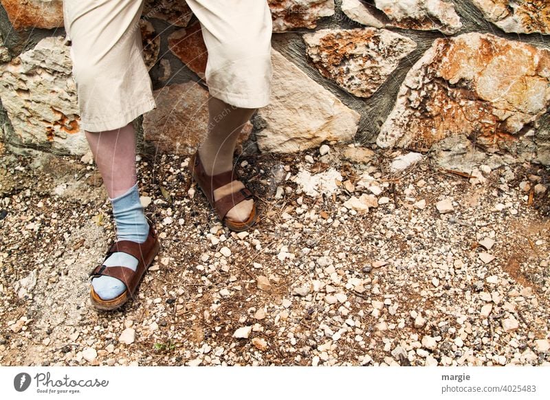 A man wears sandals with different socks Sandals Fashion Man Legs Feet Exterior shot Wall (barrier) Stony Footwear Curiosity stony road Human being Pants Adults