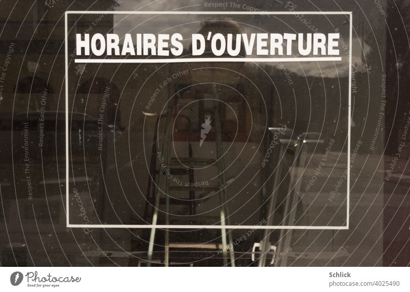 Selfie with breathing mask in front of an empty shop window with French inscription "HORAIRES D'OUVERTURE" without indication of opening hours Shop window