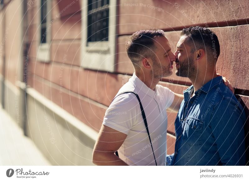 Gay couple kissing outdoors in urban background. gay men male love homosexual lgbt lgbtq relationship lovers boyfriend people adult wall happy outside together