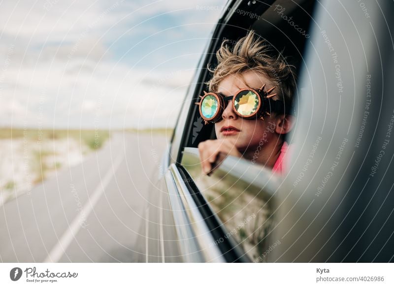 A boy looks out of a window of a moving vehicle with kaleidoscope glasses on Kaleidoscope kaleidoscope goggles road trip Vacation & Travel Vacation mood child