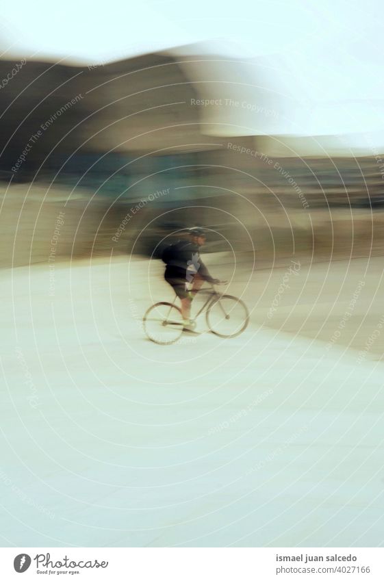 blurred cyclist on the city,  mode of tranportation biker bicycle transportation cycling biking exercise activity lifestyle ride speed fast motion movement