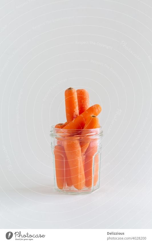 Group of orange carrots in a glass jar on white background, with copy space, vegan snack health color vitamin freshness above breakfast closeup delicious detox