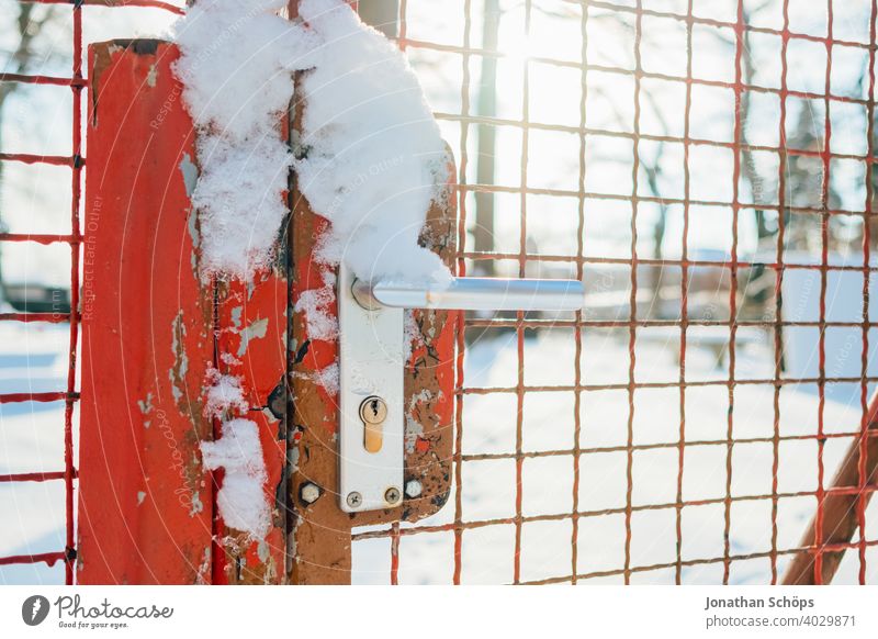 red metal fence with gate in winter with snow Entrance Grating lattice fence Door handle Real estate Property line Metal Lock Snow sunshine Goal door handle