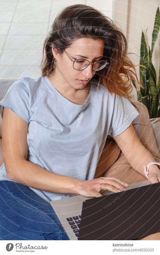 Young women using laptop while sitting on the sofa at home wear mockup t-shirt learn student Lifestyle jeans glasses serious concentrated indoor couch
